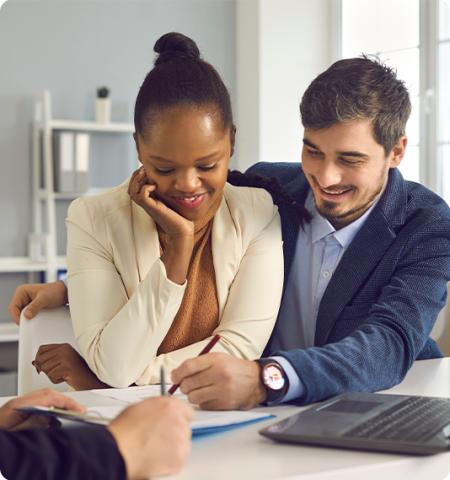 younger couple signing a document while another person looks on.